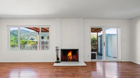 an empty room with wooden floor fireplace and windows