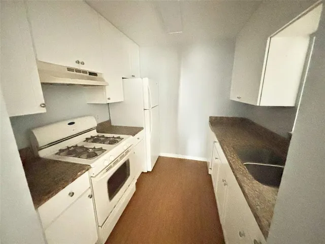 a kitchen with granite countertop a sink stove and cabinets