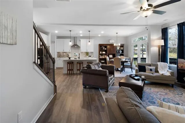 a living room with furniture kitchen view and a wooden floor