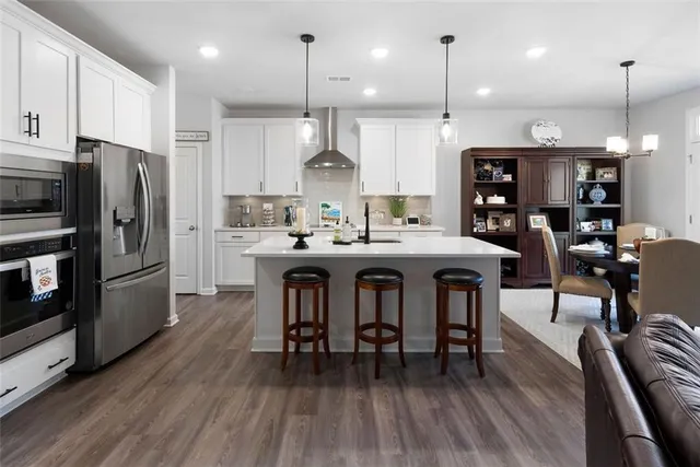 a kitchen with stainless steel appliances kitchen island a refrigerator and a wooden floor