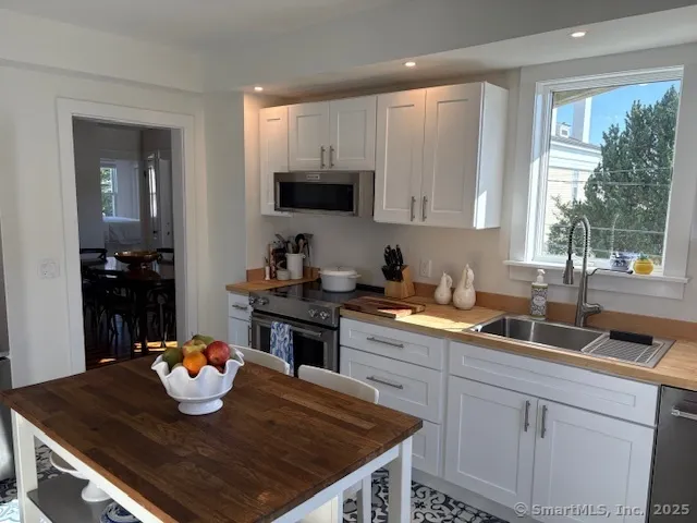 a kitchen with kitchen island granite countertop a sink dishwasher stove and cabinets