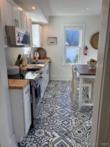 a kitchen with stainless steel appliances a sink a stove a refrigerator a dining table and chairs