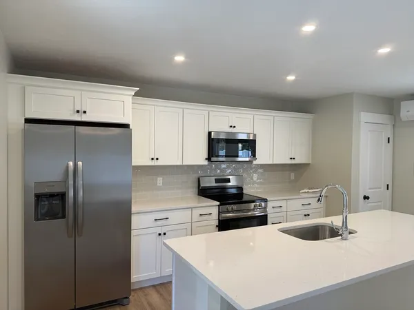 a kitchen with stainless steel appliances a refrigerator sink and white cabinets