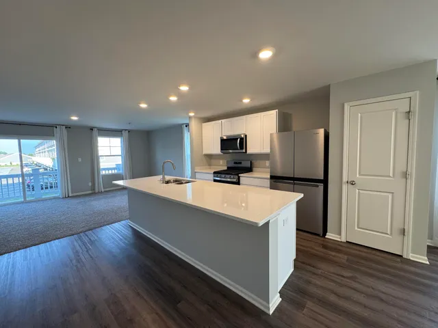 a large kitchen with a center island wooden floor and stainless steel appliances