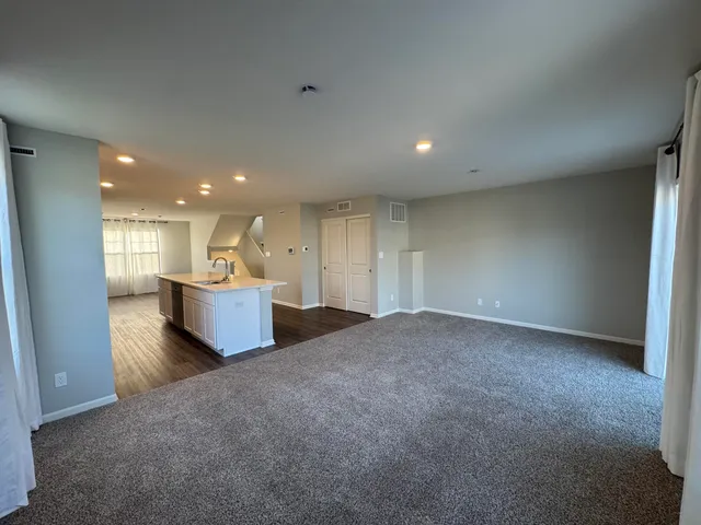 a view of a big room with wooden floor and a kitchen