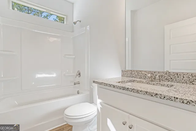 a bathroom with a granite countertop sink a toilet and shower