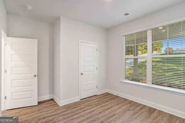 a view of an empty room with wooden floor and a window