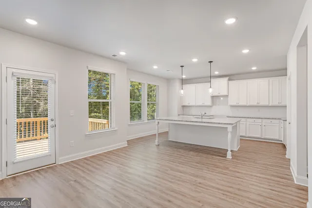 a large white kitchen with white cabinets and wooden floor