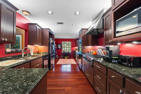 a open kitchen with stainless steel appliances granite countertop a refrigerator dining table and chairs with wooden floor