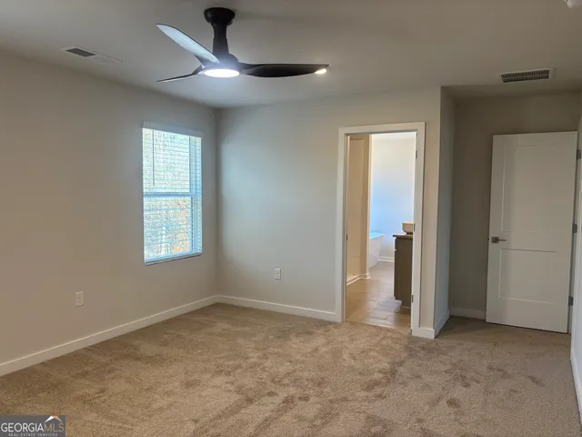 an empty room with a chandelier fan and windows