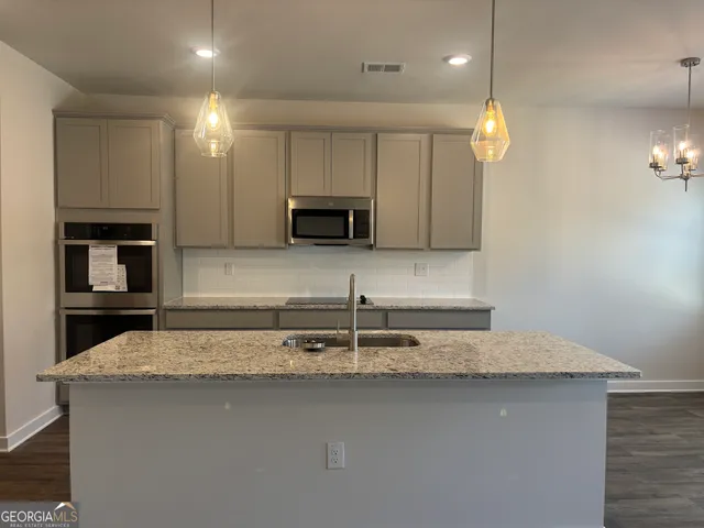 a kitchen with kitchen island granite countertop a sink and a stove top oven