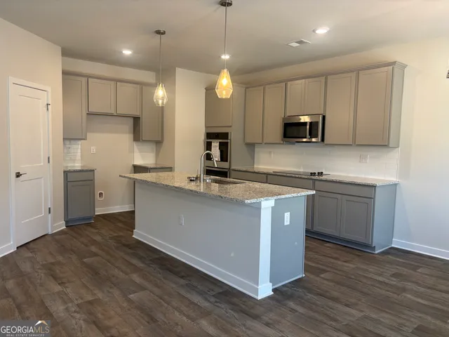 a kitchen with stainless steel appliances granite countertop a sink a stove a refrigerator and a microwave