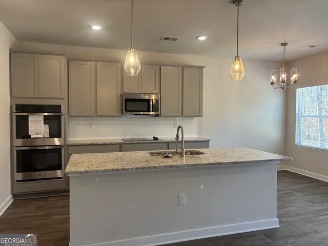 a kitchen with kitchen island granite countertop a sink a counter space appliances and cabinets