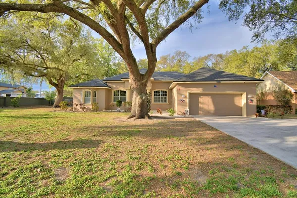 a front view of a house with a garden and trees