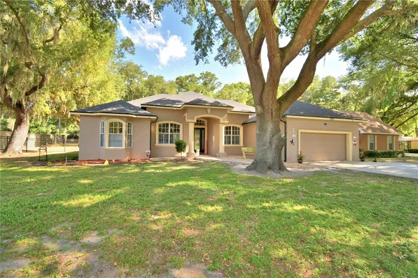 a front view of a house with a garden and trees