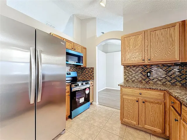a kitchen with granite countertop a refrigerator and a stove top oven