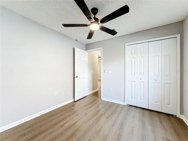 an empty room with wooden floor ceiling fan and windows