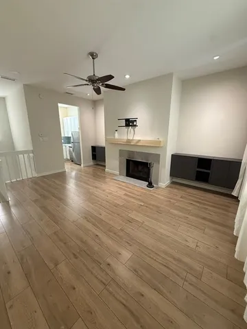 an empty room with wooden floor fireplace and windows