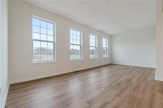 a view of an empty room with wooden floor and window
