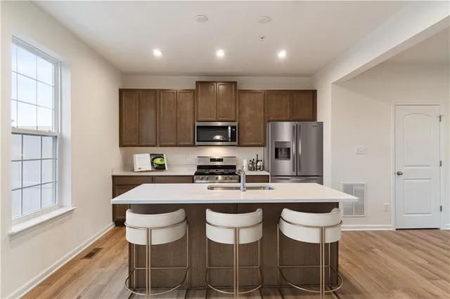 a kitchen with kitchen island granite countertop a dining table chairs refrigerator and cabinets