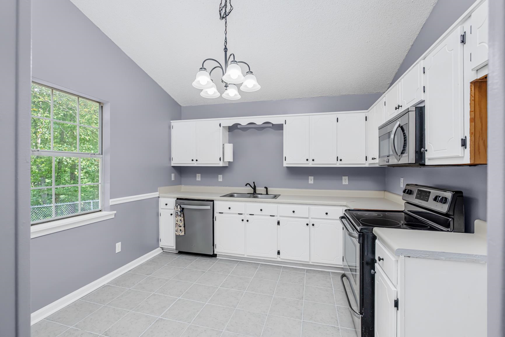 260 Chisolm Trail Road Atoka, TN 38004 - Photo 12 of 30 a kitchen with stainless steel appliances granite countertop white cabinets a sink a window and white stainless steel appliances