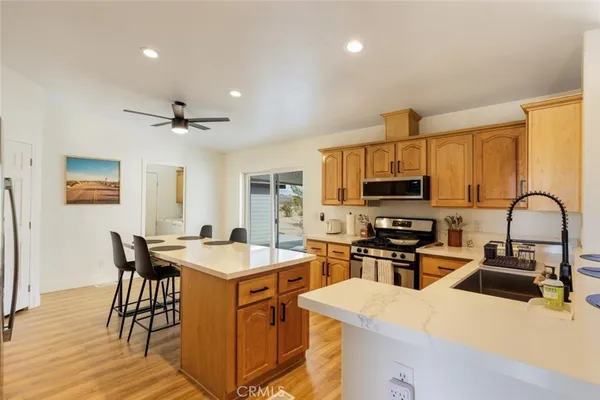 a kitchen with stainless steel appliances granite countertop a stove top oven a sink a dining table and chairs with wooden floor