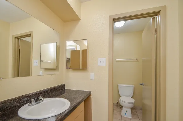 a bathroom with a granite countertop sink toilet a mirror and shower