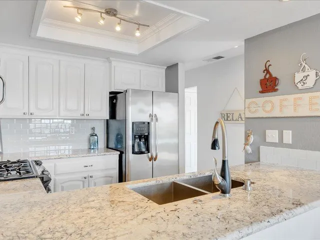 a kitchen with stainless steel appliances kitchen island granite countertop a refrigerator and a sink