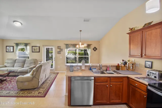 a kitchen with granite countertop a sink dishwasher a stove and white cabinets with wooden floor