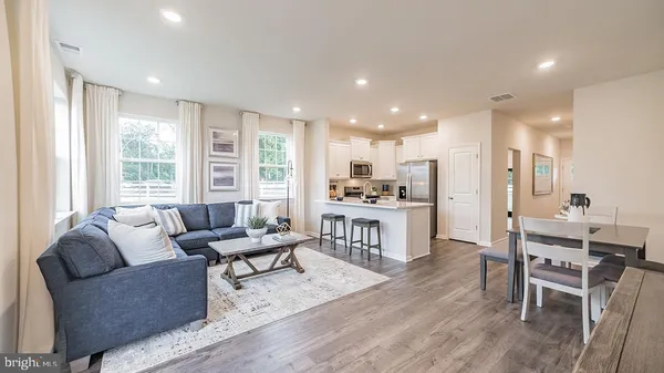 a living room kitchen with furniture and kitchen view with wooden floor