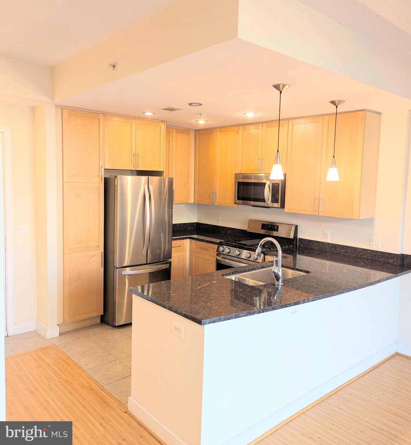 820 North Pollard Street, Unit 810 Arlington, VA 22203 - Photo 3 of 49 a kitchen with kitchen island a counter top space a sink a refrigerator and a window