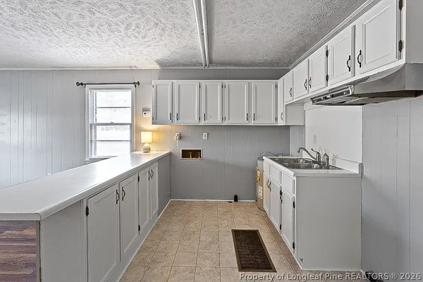 a kitchen with a sink a stove cabinets and wooden floor