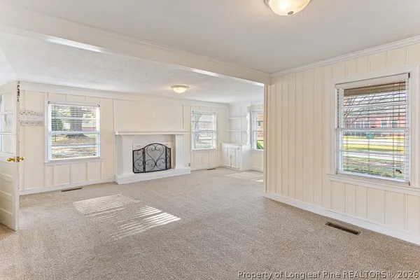an empty room with windows and fireplace