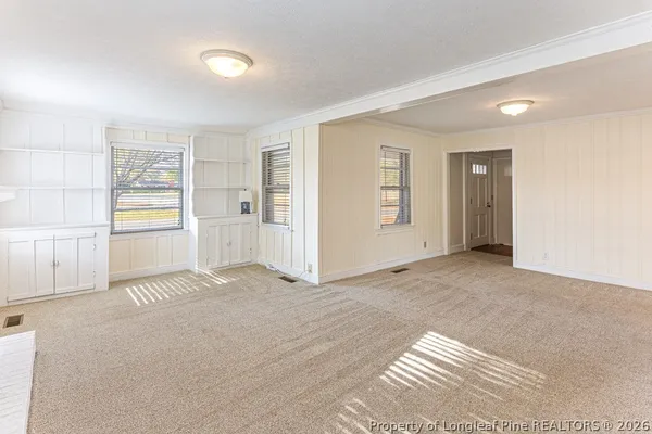 a view of an empty room with window and a kitchen
