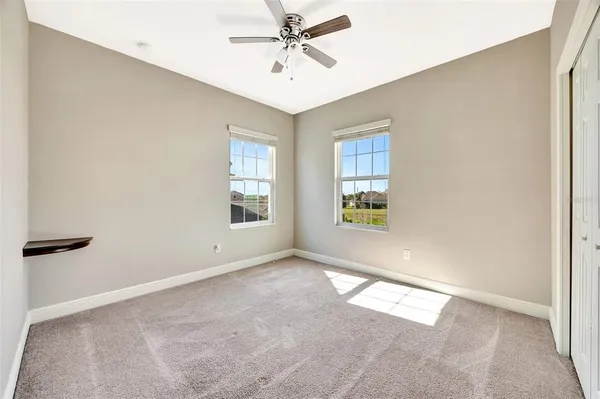 an empty room with windows and fan