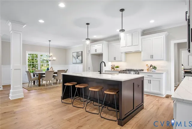 a open kitchen with stainless steel appliances granite countertop a stove a sink dishwasher a refrigerator island and chairs with wooden floor