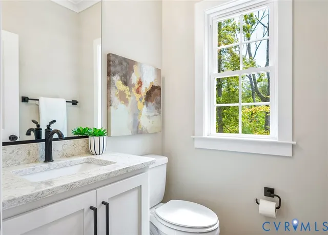 a bathroom with a granite countertop sink and a toilet