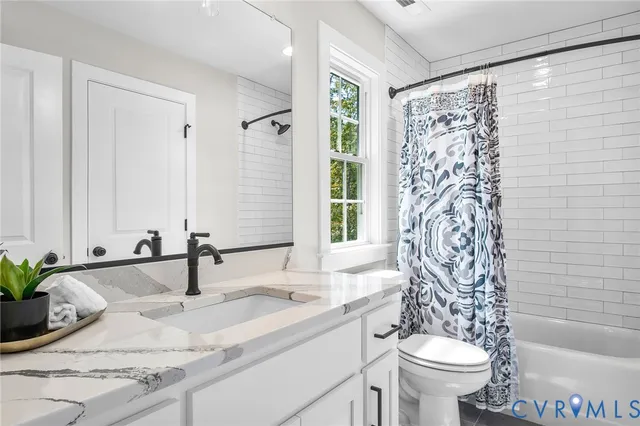 a bathroom with a granite countertop sink and a toilet