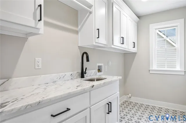 a bathroom with granite countertop white cabinets and a sink