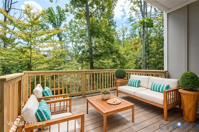 a balcony of a house with wooden floor outdoor seating and yard in the back