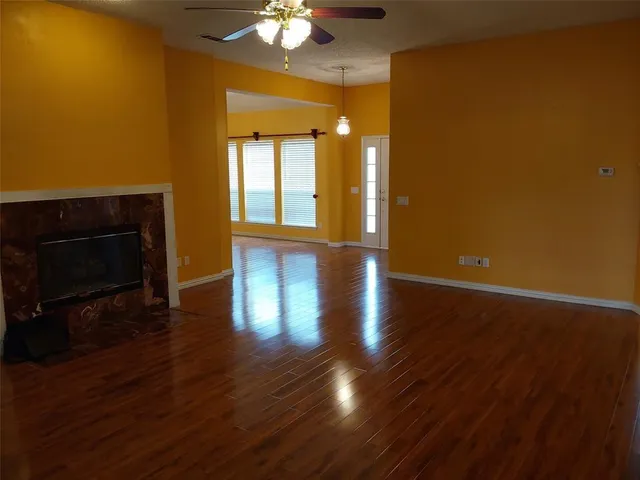 a view of an empty room with wooden floor and a fireplace