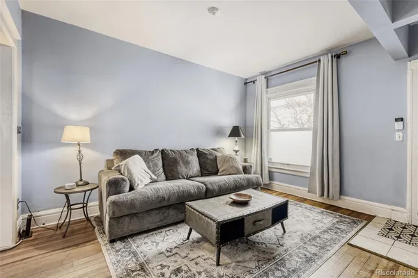 a living room with furniture a rug a lamp and a window