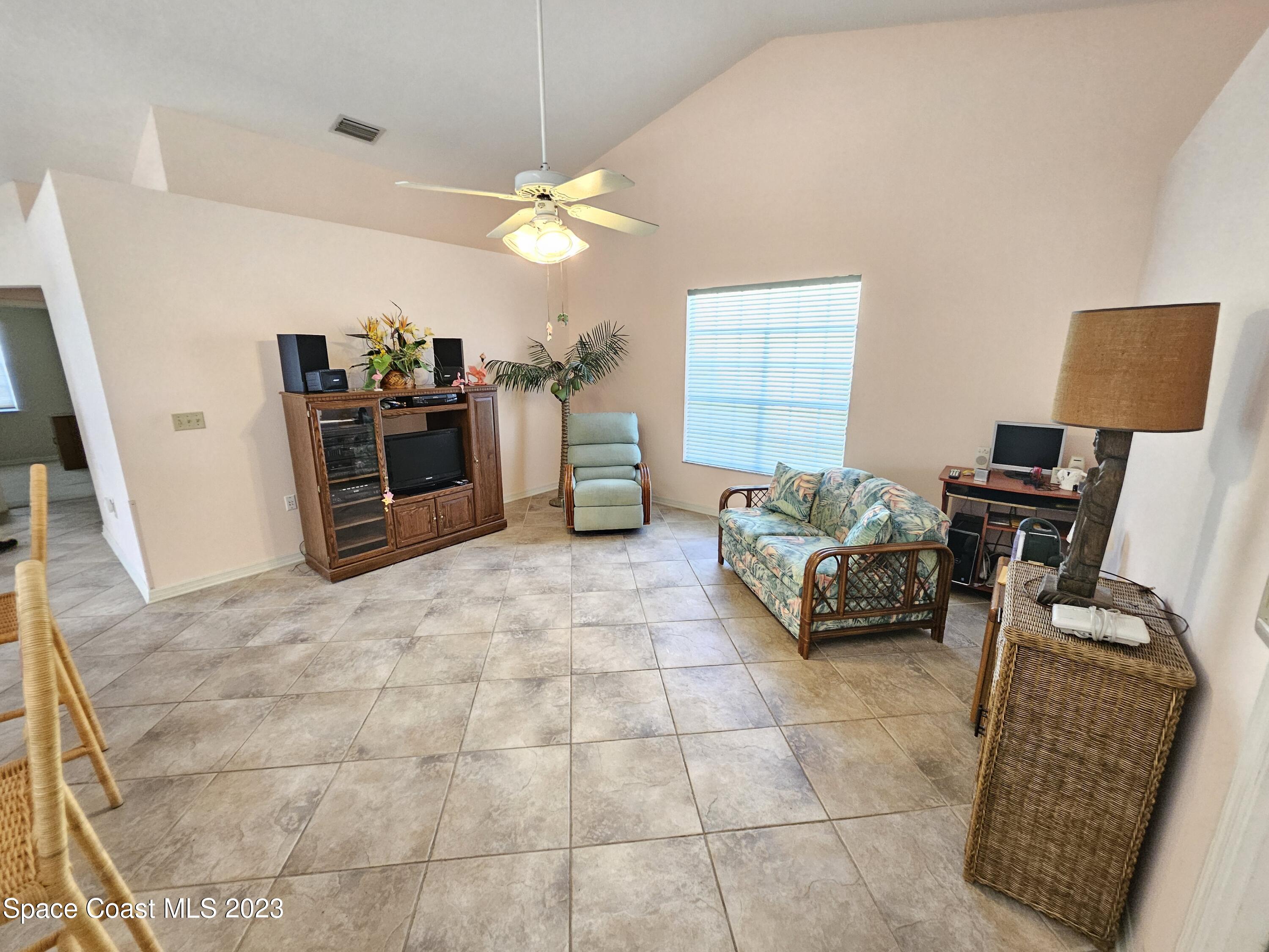 1910 Glen Meadows Circle Melbourne, FL 32935 - Photo 12 of 28 a living room with furniture a chandelier and a flat screen tv