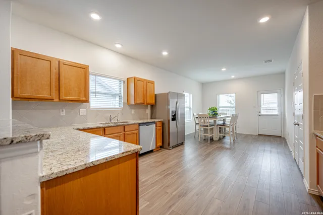 a kitchen with stainless steel appliances granite countertop wooden cabinets a sink a stove a dining table and chairs