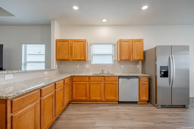 a kitchen with stainless steel appliances granite countertop a refrigerator and a sink