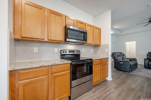 a kitchen with stainless steel appliances granite countertop a stove top oven a sink dishwasher and wooden cabinets with wooden floor