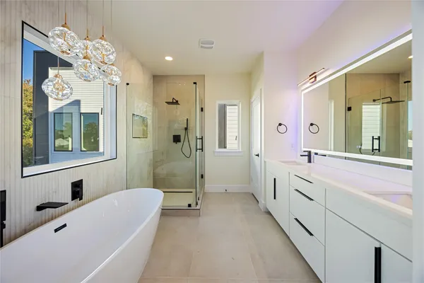 a spacious bathroom with a tub sink shower and mirror