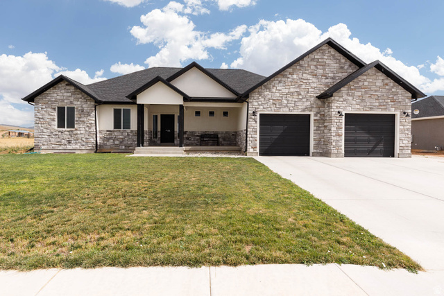 View of front of home featuring a porch, a front lawn, driveway, and an attached garage