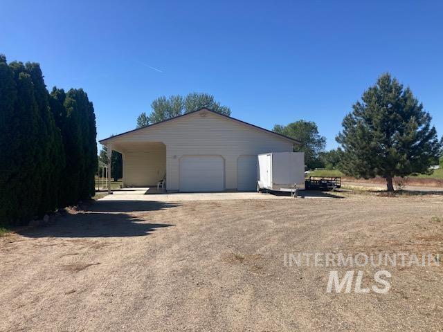 1095 County Road 70 Weiser, ID 83672 - Photo 28 of 44 Detached garage structure featuring a single garage door, an open carport, and light-colored siding