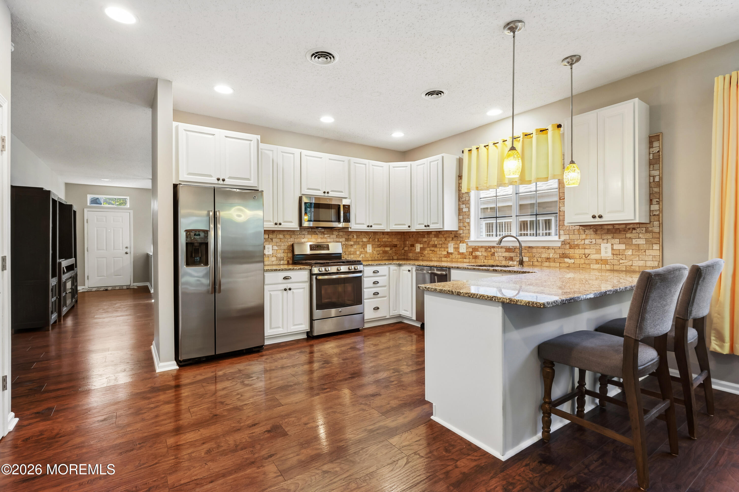 66 Sandpiper Road Barnegat, NJ 08005 - Photo 8 of 25 a kitchen with stainless steel appliances granite countertop a refrigerator a stove a sink a dining table and chairs with wooden floor
